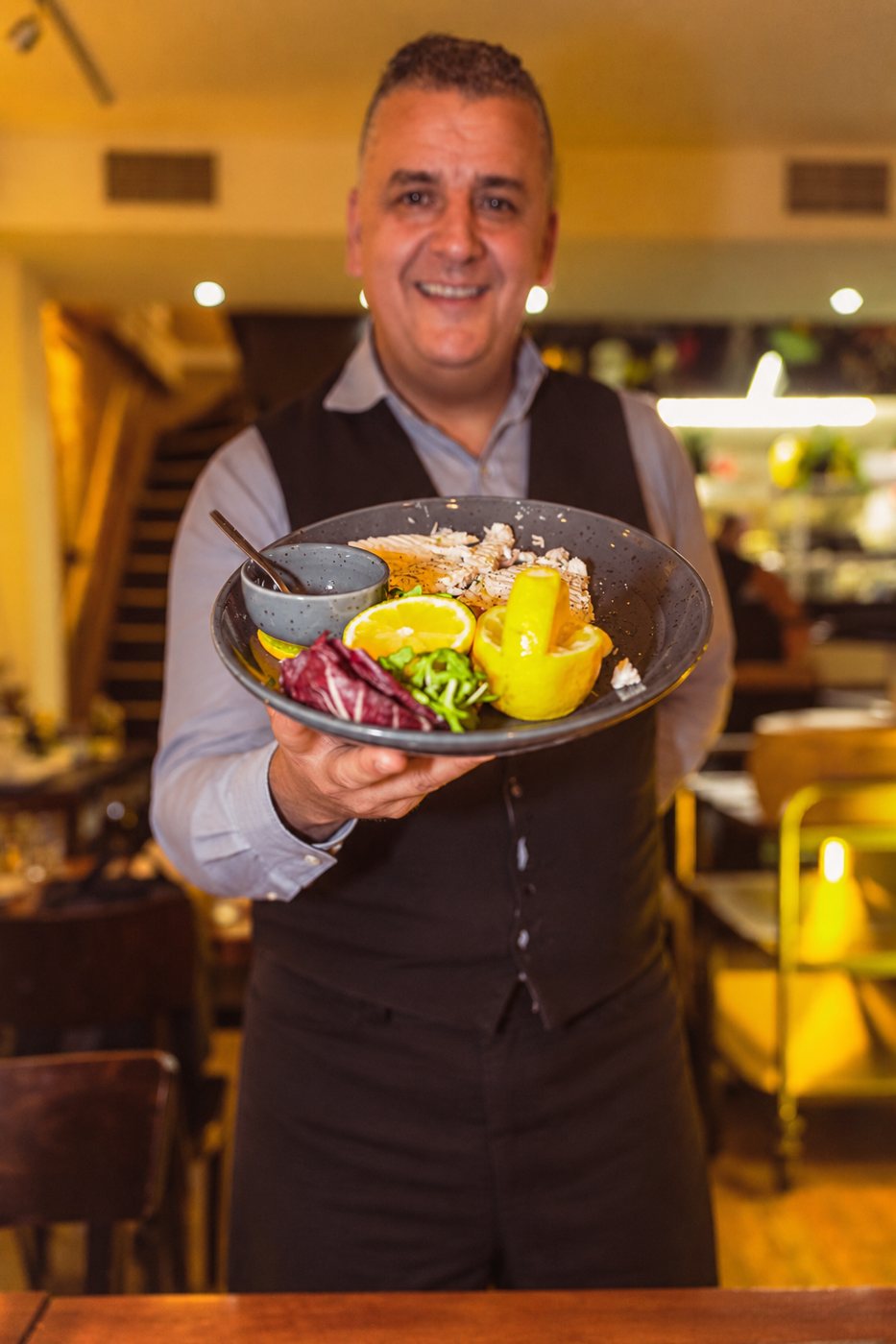 Gastheer Massimo serveert een gerecht bij Italia Oggi in Amsterdam
